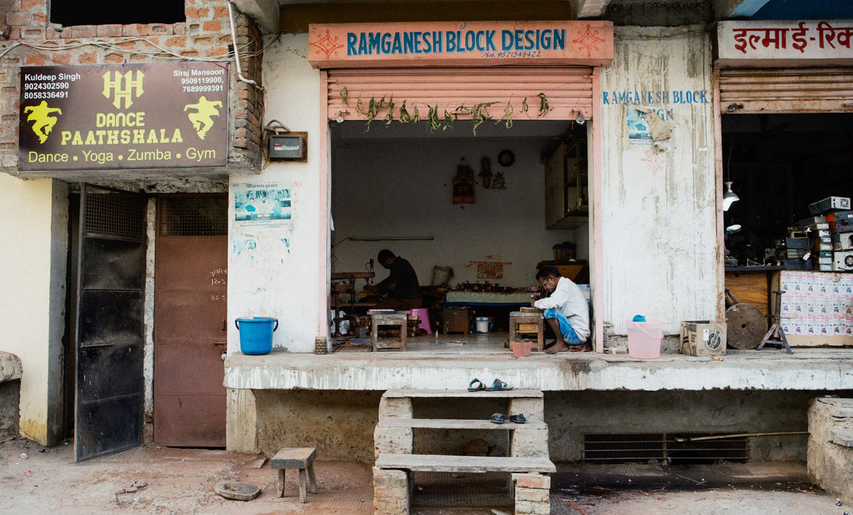The open front of a block design workshop, two people at work inside